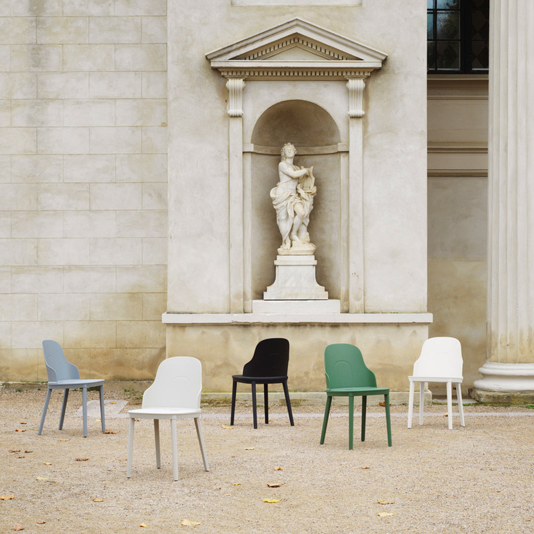 Set of six minimalist chairs in gray, white, black, green, and muted tones, displayed against a classic stone backdrop.