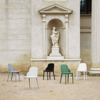 Set of six minimalist chairs in gray, white, black, green, and muted tones, displayed against a classic stone backdrop.