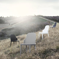 Four modern chairs in black, white, gray, and muted tones set against a serene hillside backdrop.