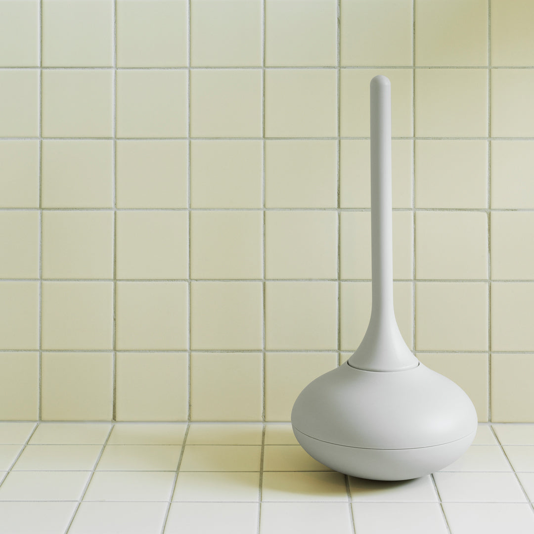 Sleek white toilet plunger against a pale yellow tiled wall for a modern bathroom look.