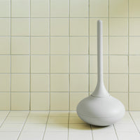 Sleek white toilet plunger against a pale yellow tiled wall for a modern bathroom look.
