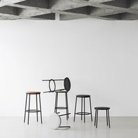Five stylish bar stools in black and brown, featuring sleek modern designs and varying heights on a minimalistic backdrop.
