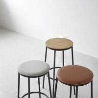 Set of three modern bar stools featuring gray, brown, and natural wood seats with sleek black metal legs.