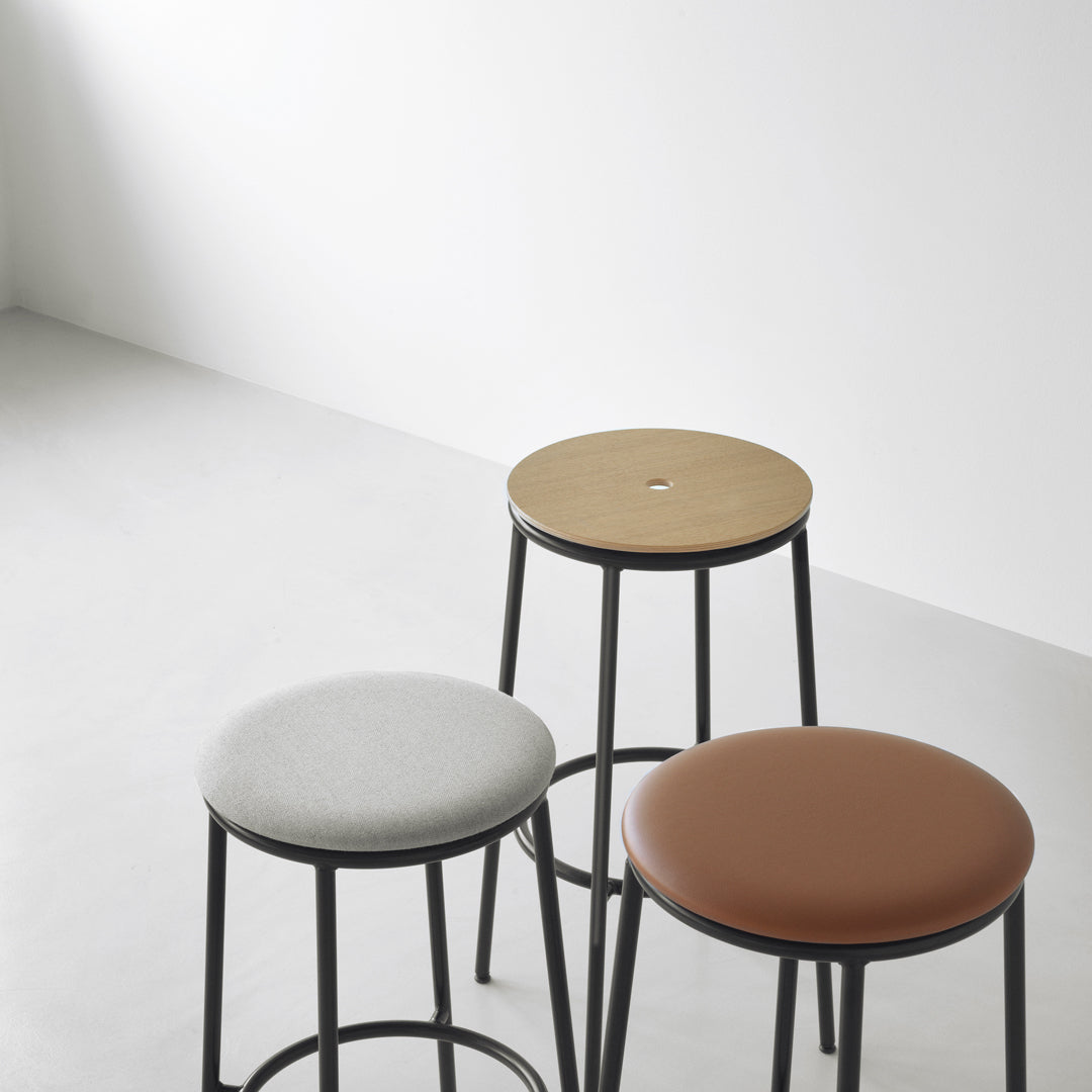 Three stylish stools featuring grey, tan, and brown cushioned seats on sleek black metal frames.
