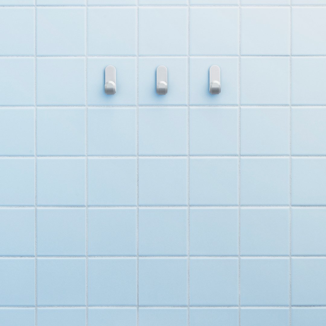 Light blue tiled wall featuring three white hooks for a clean and modern look.
