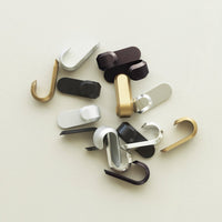 Assorted hooks in gold, silver, black, and brown with sleek, modern designs on a neutral background.