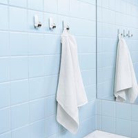 White towels hanging on hooks against a light blue tiled bathroom wall, creating a fresh and clean aesthetic.