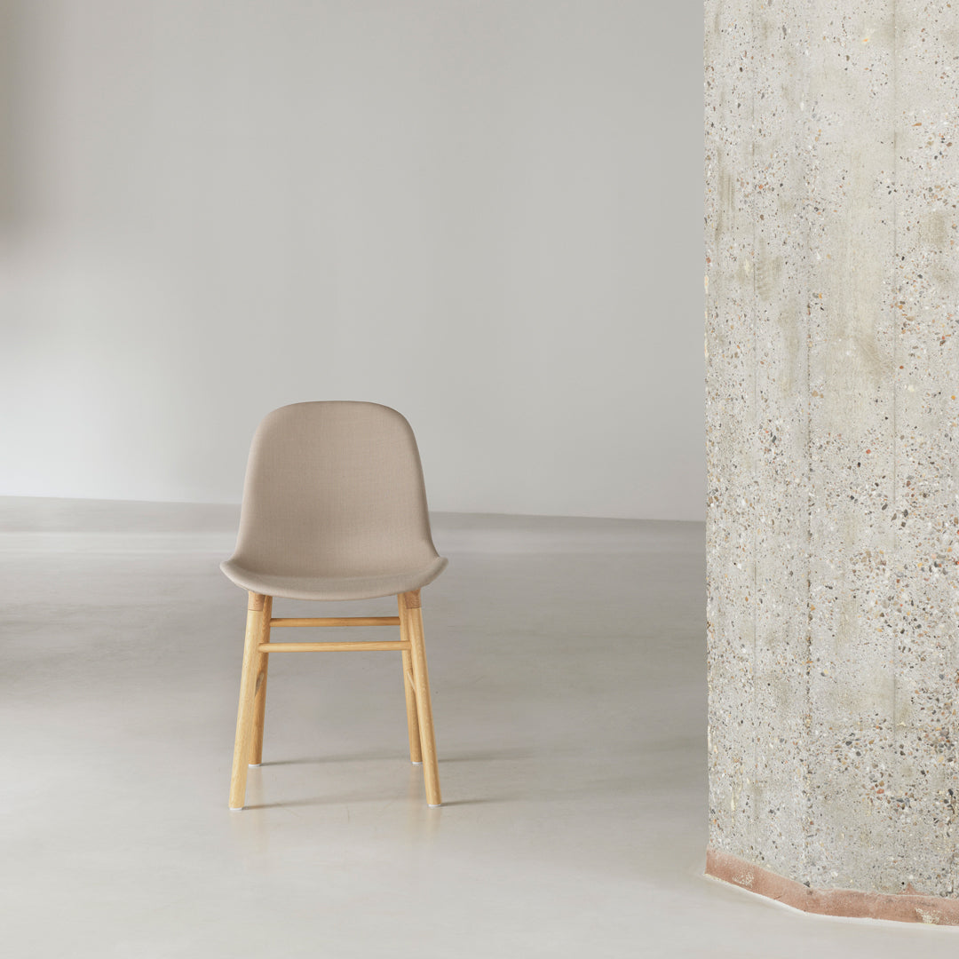 Beige chair with a smooth finish and natural wood legs, set against a minimalist, light gray background.