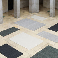 "Textured area rugs in grey, white, dark green, and black patterns on a tiled floor."