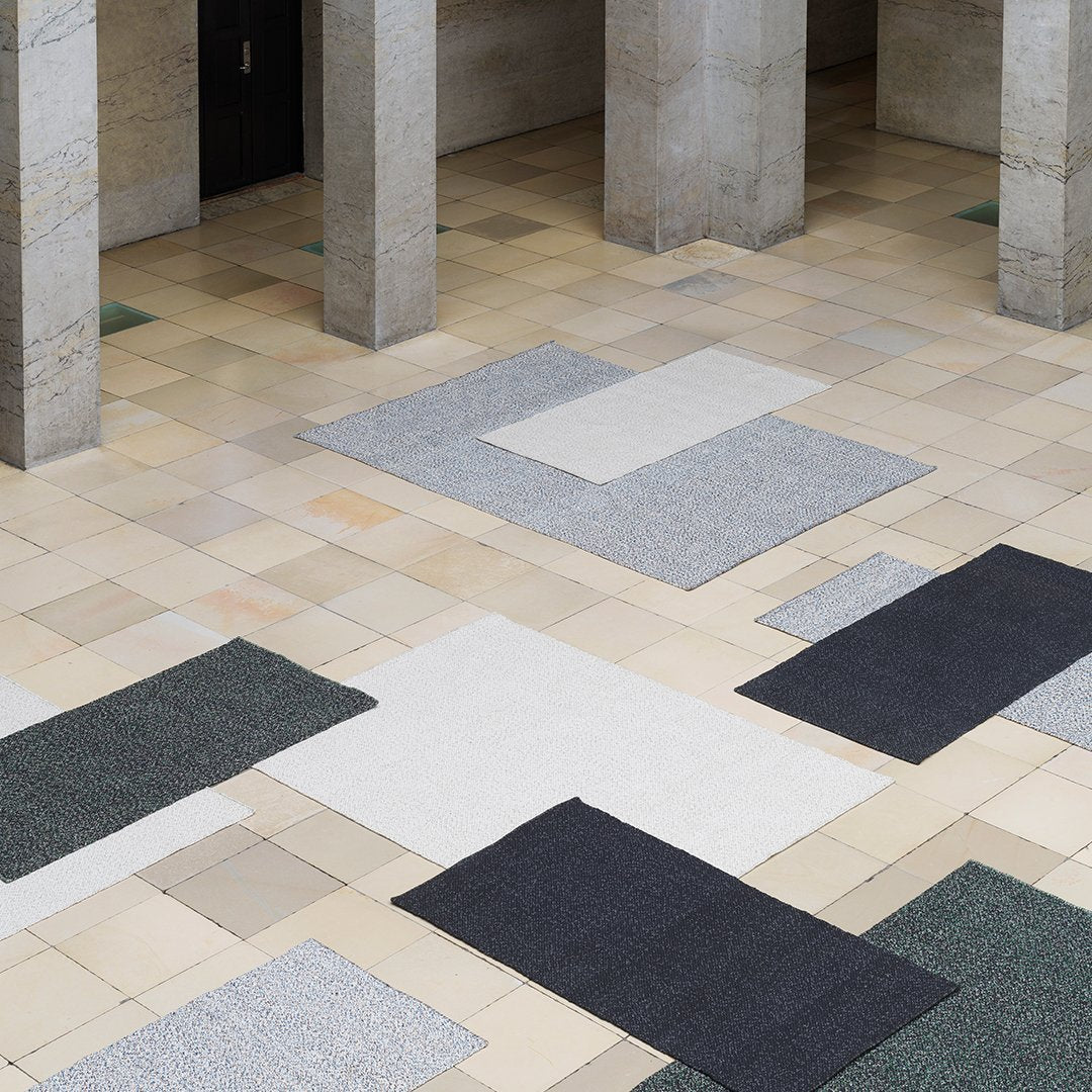 "Textured area rugs in grey, black, and white patterns on a tiled floor, creating a modern aesthetic."