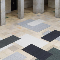 "Textured area rugs in grey, black, and white patterns on a tiled floor, creating a modern aesthetic."