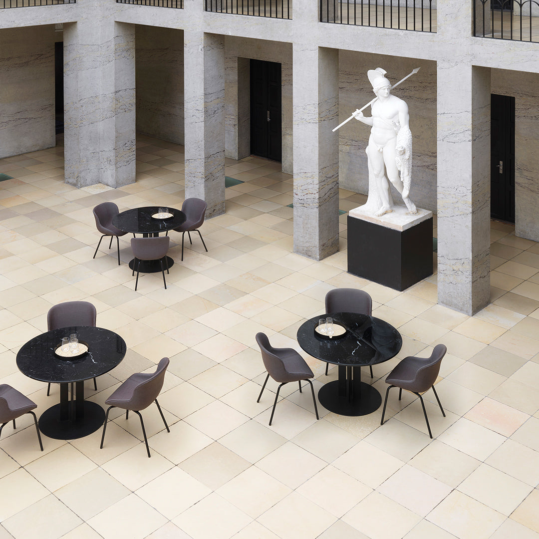 "Elegant black tables with modern gray chairs on a light beige tiled floor, accented by a classic white statue."