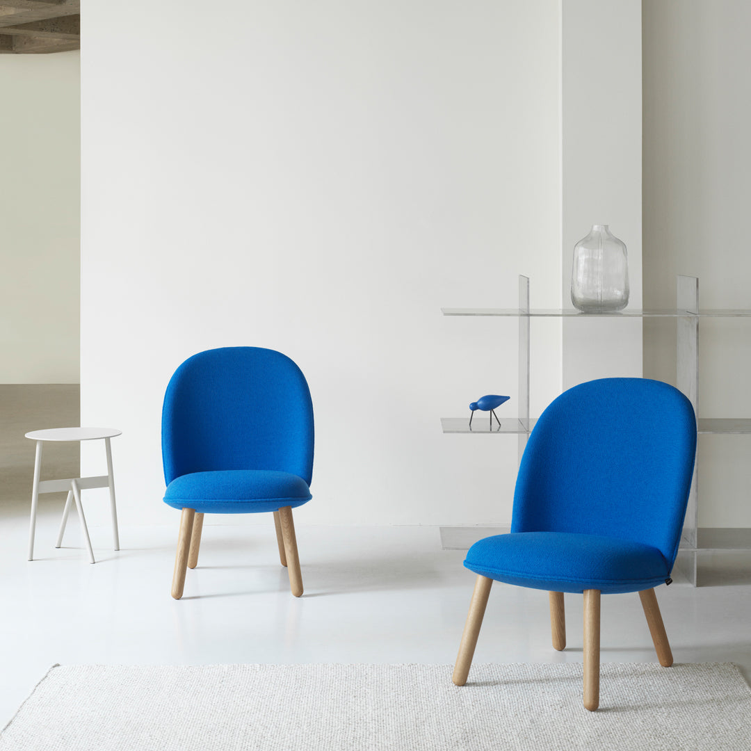 Blue upholstered chairs with wooden legs in a minimalist setting. Modern design with a vibrant color contrast.