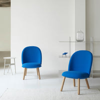 Blue upholstered chairs with wooden legs in a minimalist setting. Modern design with a vibrant color contrast.