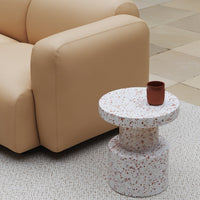 "Round terrazzo side table in white with red speckles, paired with a minimalistic brown ceramic cup."