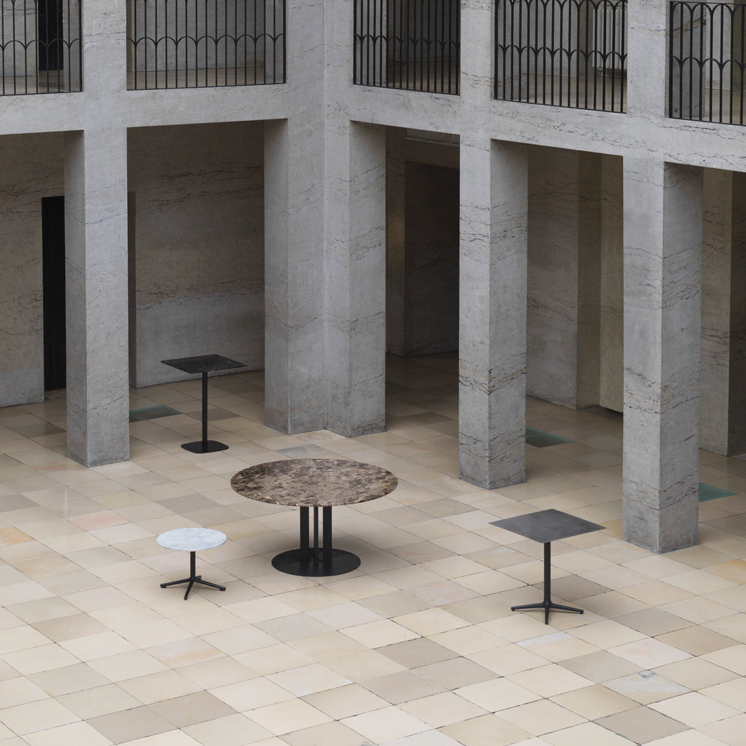 "Stylish tables in shades of gray, black, and white with modern textures, set against a minimalist stone backdrop."