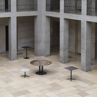 "Stylish tables in shades of gray, black, and white with modern textures, set against a minimalist stone backdrop."