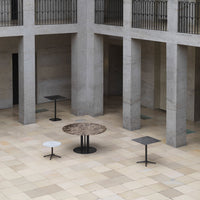 Modern tables featuring earthy tones, sleek black bases, and unique circular and rectangular patterns in an open space.