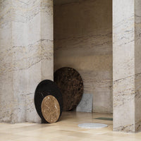 Stylish round rugs in black, white, and gold hues with textured patterns, set against a minimalist background.