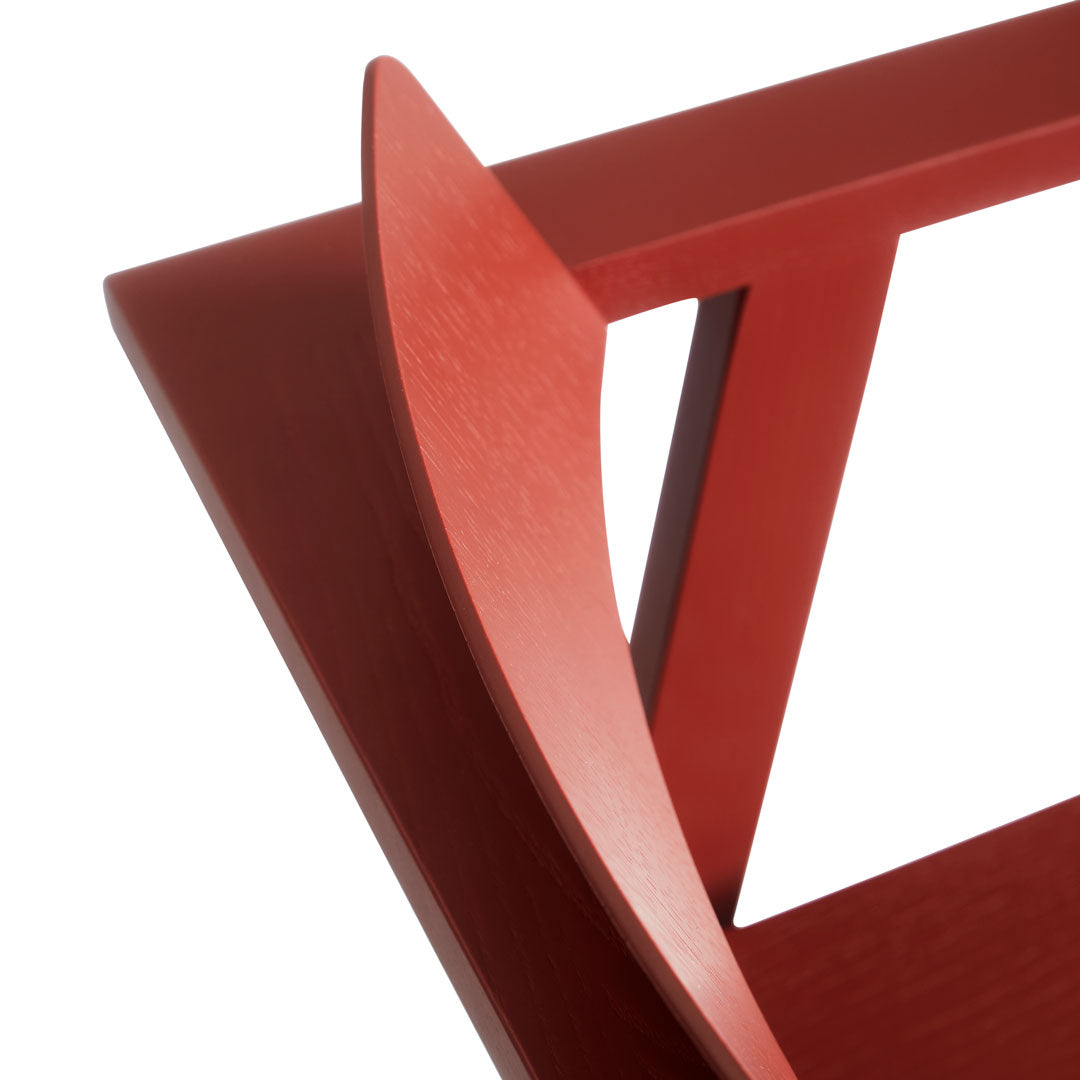 Red wooden chair with sleek lines and a modern design showcasing a smooth, rich finish.