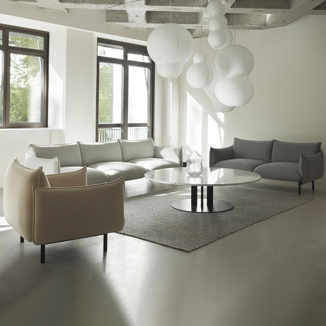 Stylish gray and cream sofas with a sleek gray area rug and white spherical pendant lights in a modern living room.