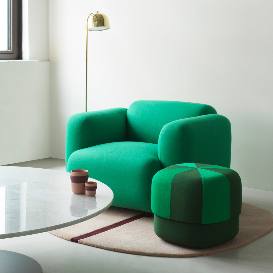 Vibrant green armchair and matching ottoman with contrasting patterns, set against a minimalistic interior.
