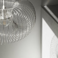 Silver wire pendant light casting intricate shadows on a gray wall, showcasing a modern, minimalist design.