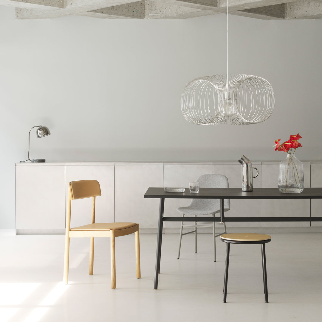 Modern dining room featuring minimalist gray walls, a sleek black table, natural wood tones, and a unique transparent pendant light.