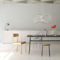 Modern dining room featuring minimalist gray walls, a sleek black table, natural wood tones, and a unique transparent pendant light.