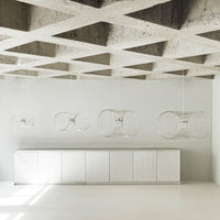 Modern white pendant lights against a textured gray ceiling and sleek white cabinetry. Minimalist design with clean lines.