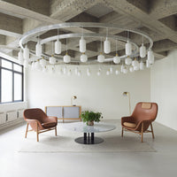"Modern living room with brown leather chairs, a round black coffee table, and white pendant lights against a concrete ceiling."