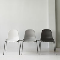 Set of three modern chairs in white, gray, and black with sleek, minimalist design and metal legs.