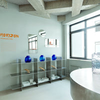 Modern decor featuring blue glass vases, clear shelves, and a neutral-toned wall with minimalist design elements.