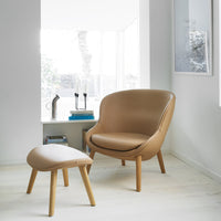 Tan leather chair with matching ottoman, featuring smooth textures and minimalist design in a bright, airy setting.