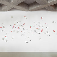 Colorful wall art featuring red, black, and white circles in varying sizes against a clean white background.
