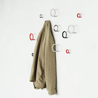 Beige jacket hanging on wall hooks; red, white, and black circular patterns create a modern, stylish look.