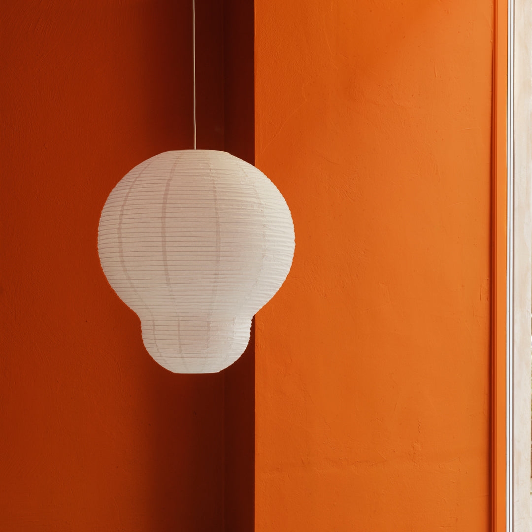 White paper lantern against a vibrant orange wall, showcasing a modern minimalist design.