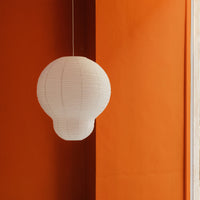 White paper lantern against a vibrant orange wall, showcasing a modern minimalist design.