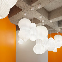 White hanging lanterns against an orange accent wall and a textured gray ceiling, creating a modern and vibrant atmosphere.