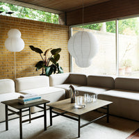 Neutral beige sectional sofa, minimalist black accent tables, and soft white lighting in a serene indoor setting.