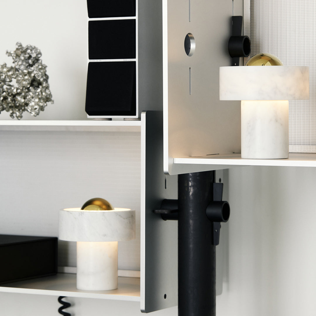 Modern decor featuring white marble lamp bases, metallic gold accents, and a minimalist black shelf design.