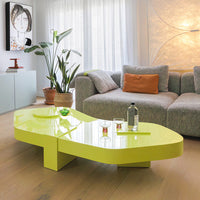 Vibrant yellow sculptural coffee table with smooth surfaces, set against a cozy gray couch and natural decor.