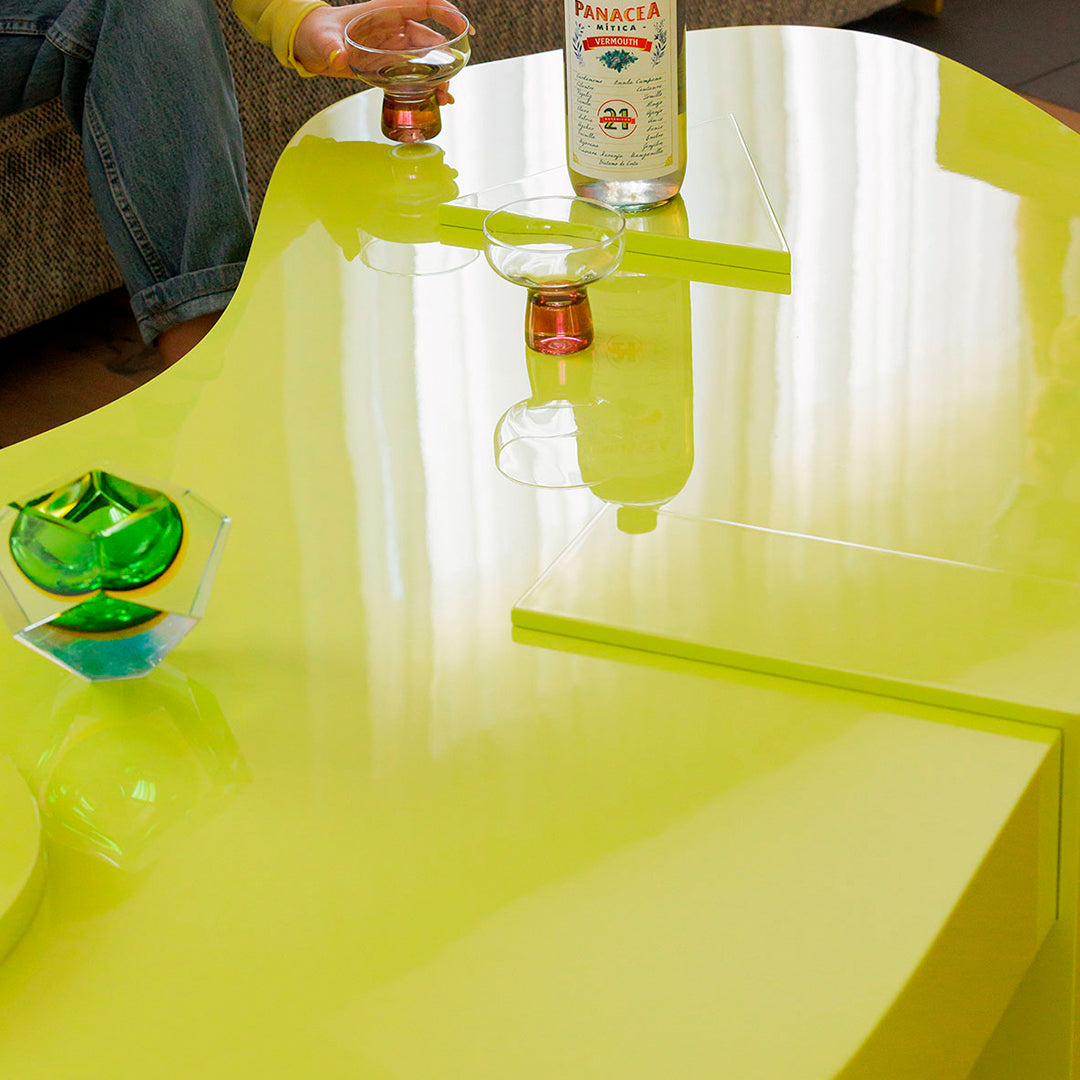 Bright lime green modern coffee table with a glossy finish, featuring smooth, curved lines and a minimalist design.