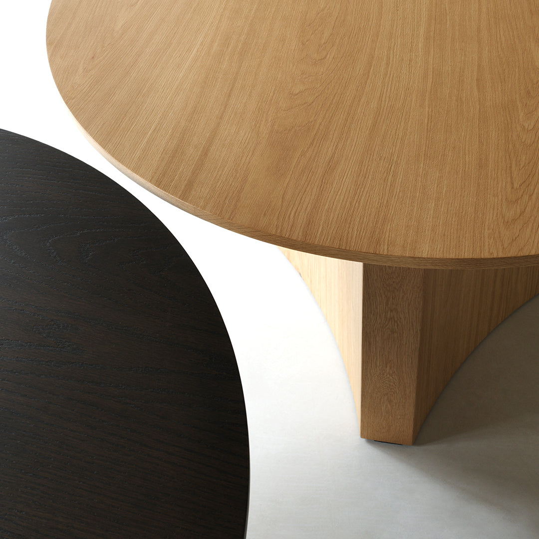 "Two modern round tabletops: one in light oak wood, the other in deep black, featuring smooth textures and clean lines."
