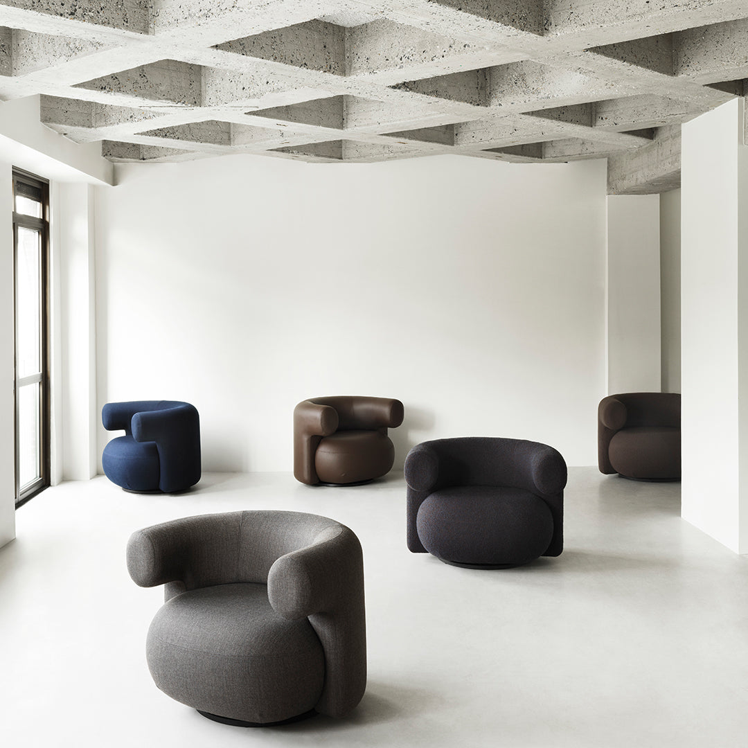 "Set of modern, round armchairs in gray, navy, dark brown, and soft-textured fabric patterns, placed in a minimalist room."