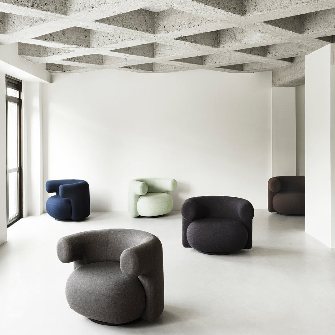 Modern chairs in gray, navy, green, and dark brown fabrics, featuring smooth, curvy patterns in a minimalist space.