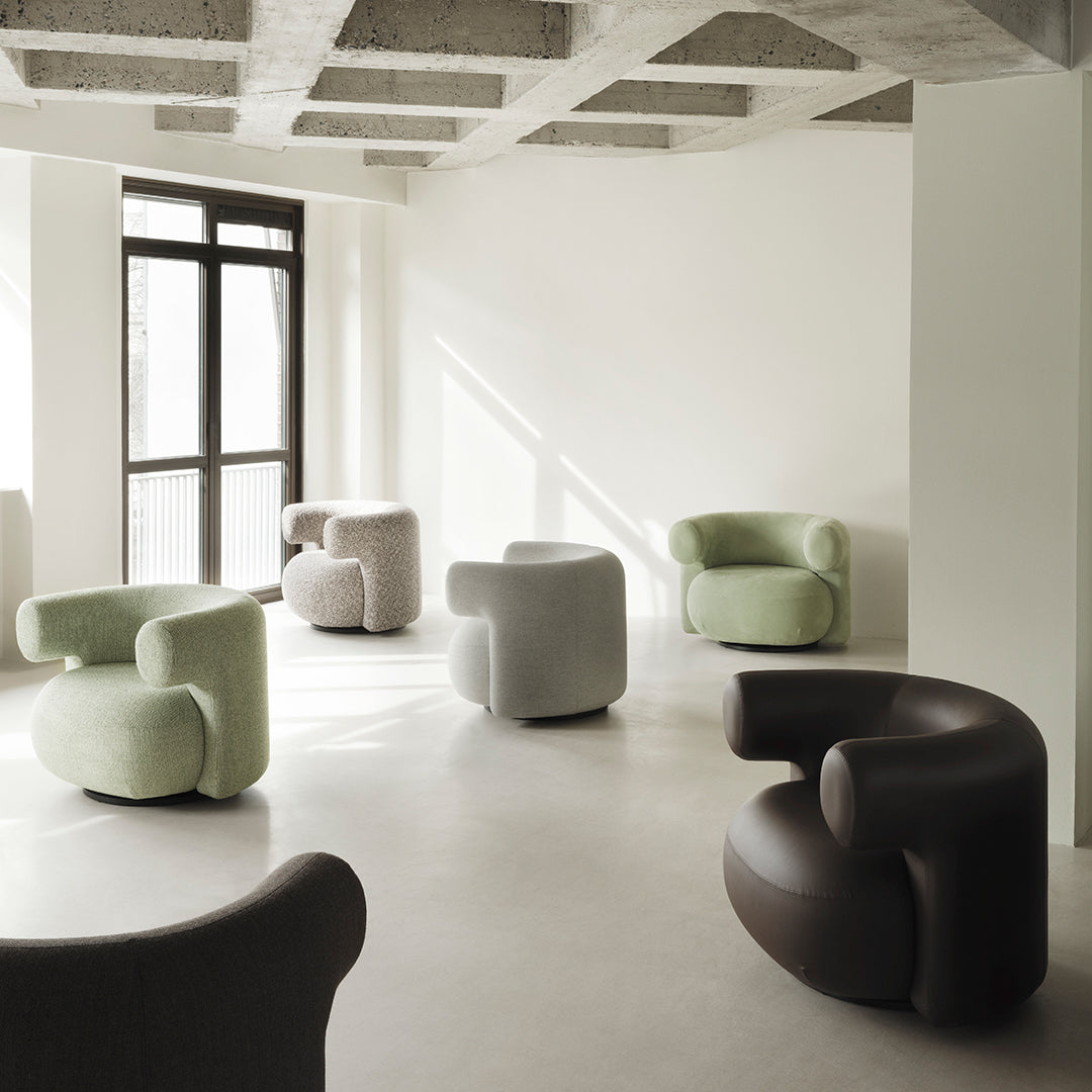 Curved lounge chairs in soft pastels, including light green, beige, and dark brown, against a minimalist backdrop.