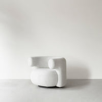 Sleek, modern white chair with rounded shapes and soft textures against a neutral background.