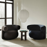 "Modern black and navy chairs with smooth curves, paired with a round wooden table in a minimalist setting."