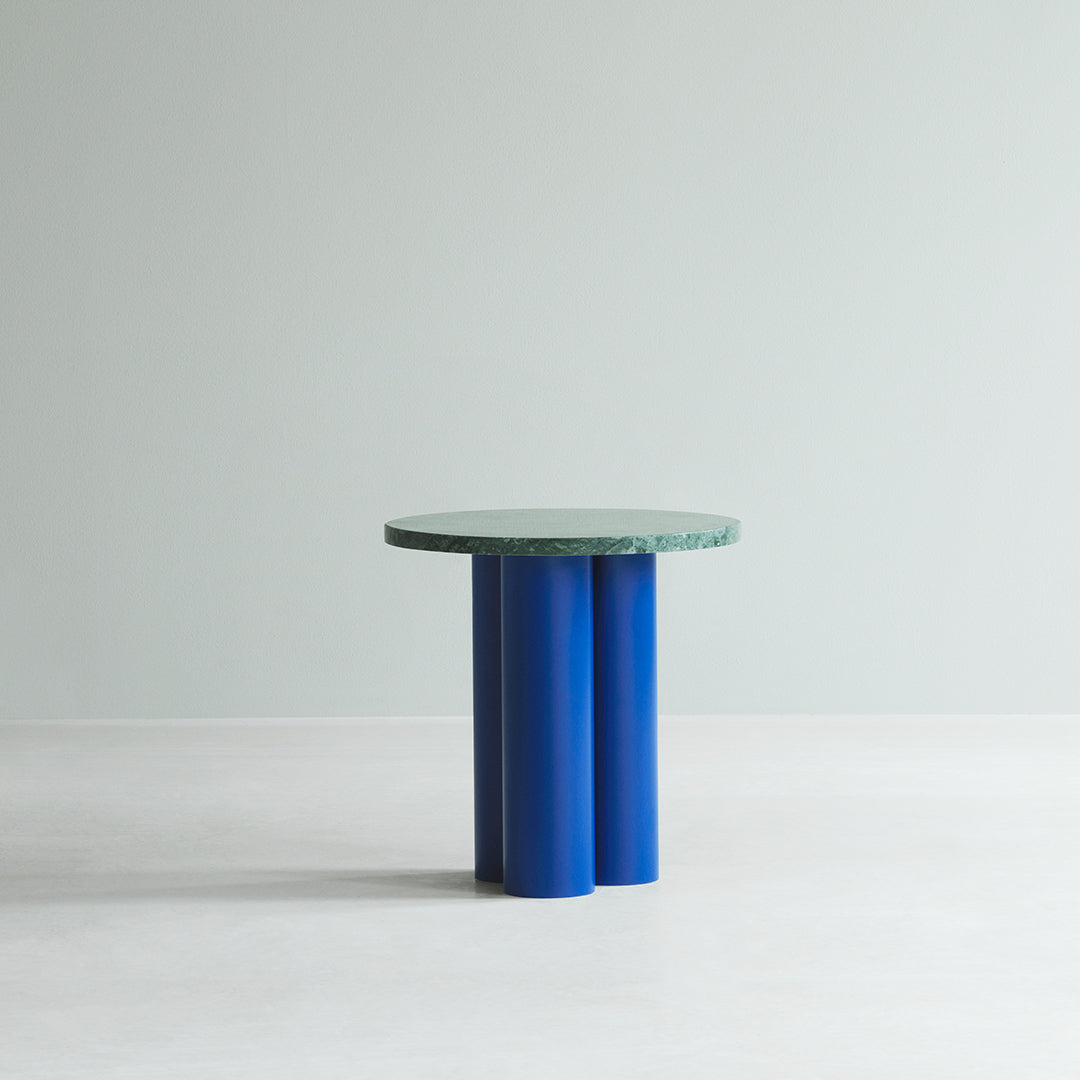Round table with a green patterned top and blue cylindrical legs against a light gray background.